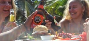 two friends saying cheers with craft beer and local beer at the restaurant in driftwood surfer hostel located in El Paredon Guatemala