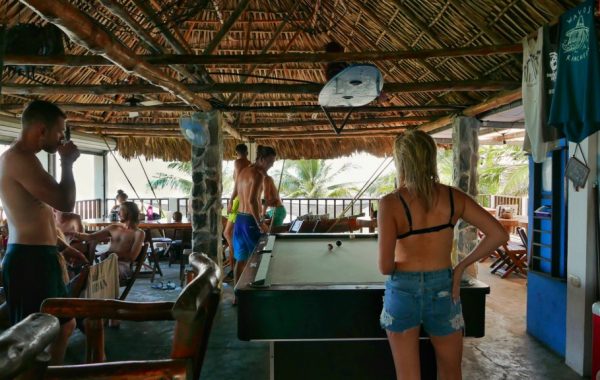 A group of travelers hiding from the sun enjoying the restaurant's pool table on the beach at El Paredon