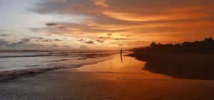a beautiful orange sunset perfectly mirrored on the black sand beach in El Paredon Guatemala
