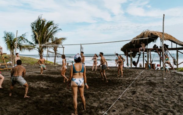 fun group of tourists enjoying a volleyball game outside The Driftwood Surfer Hostel located in El Paredon Guatemala